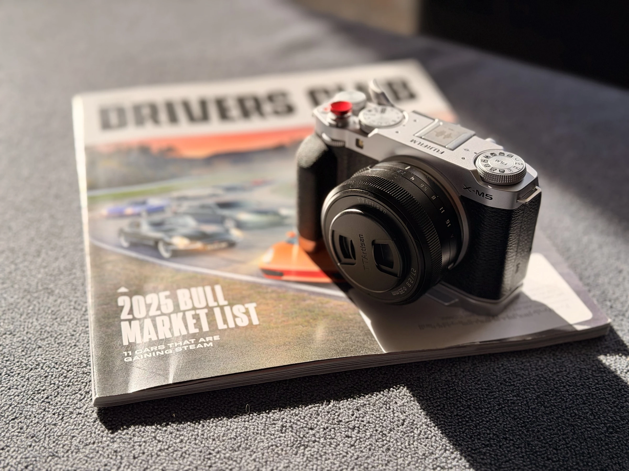 Fujifilm X-M5 with TTArtisan lens sitting on a magazine in the evening sun